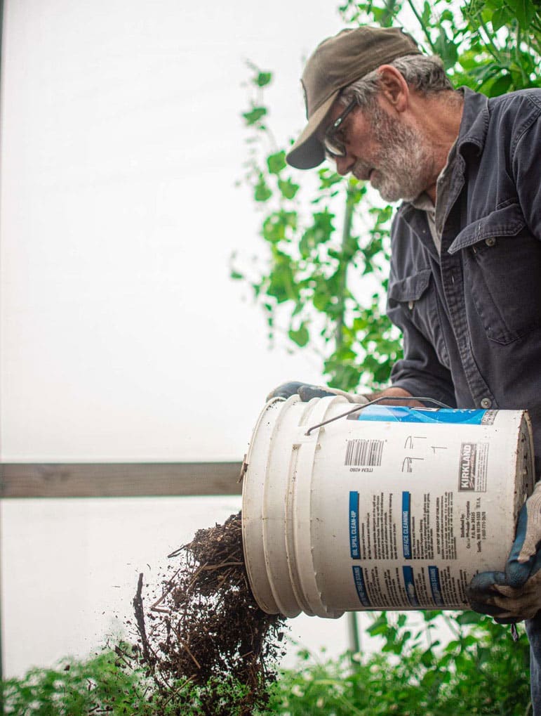 Sam Kenoyer pouring a bucket full of dirt