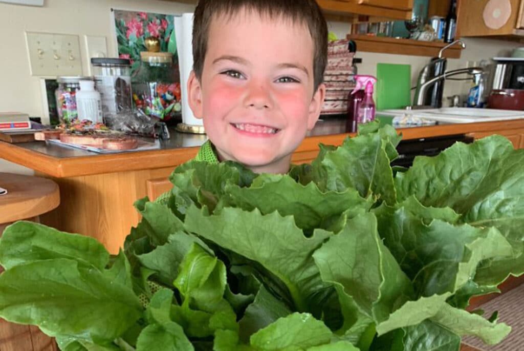 Young boy smiling next to plants